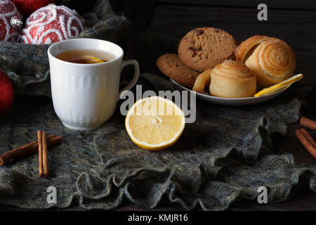 Inverno ancora vita con tè. Decorazione di natale in background. torte fatte in casa sono sul piattino. Foto Stock