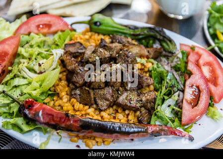 Vicino la vista dettagliata di grigliate di deliziosi piatti turchi di fegato shish kebab servito su una piastra bianca con fette di lavash,prezzemolo,onion, lattuga, pomodori ,grill Foto Stock