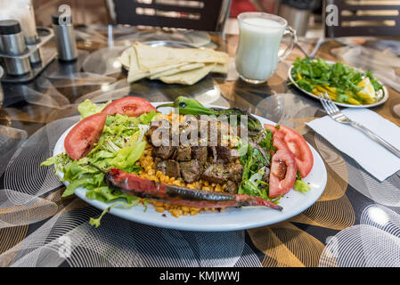 Vicino la vista dettagliata di grigliate di deliziosi piatti turchi di fegato shish kebab servito su una piastra bianca con fette di lavash,prezzemolo,onion, lattuga, pomodori ,grill Foto Stock