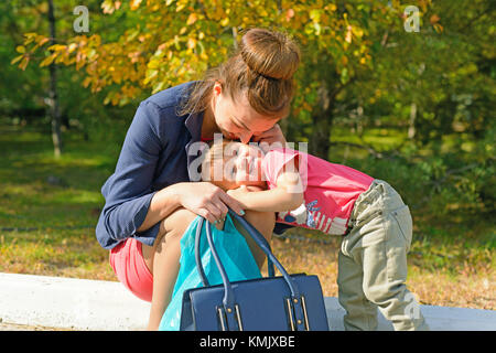 Regione di Volgograd, Russia ottobre 6, 2016. Una giovane madre seduta sul bordo del marciapiede e abbracciando il loro bambino che sorride. Foto Stock