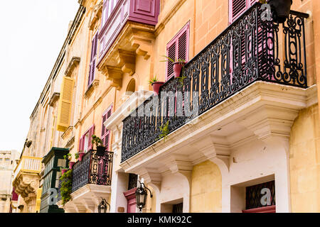 Balconi e finestre con persiane su un edificio in Maltese città fortificata di Mdina. Foto Stock