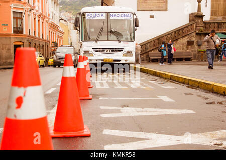 Quito, Ecuador Novembre, 28, 2017: close up sfocata coni arancione con un bus e la gente dietro nel centro storico, il trasporto pubblico della città vecchia di Quito in Ecuador settentrionale Foto Stock