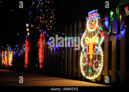 Le luci di Natale. outdoor display con pupazzo di neve e candy canes su giardino recinto. colorata e divertente vacanza celebrazione. Foto Stock