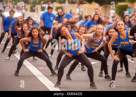 Un multirazziale di alta scuola di danza ragazze team esegue mentre marcia in una città parata anniversario in fountain valley, ca. Foto Stock