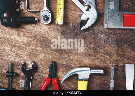 Vista superiore di strumenti di lavorazione,dinamometrica,chiave a brugola,martello,cacciavite,pinza,trapano elettrico,flessometro,macchinista square e occhiali di sicurezza con dorso in legno Foto Stock