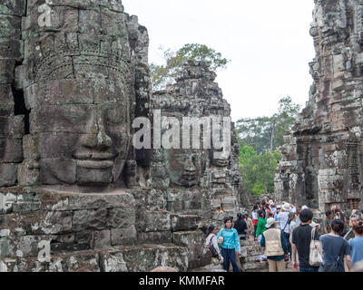 Ai turisti di ammirare la serena sorridente stone faces in a Bayon Angkor Thom in Siem Reap, Cambogia. Foto Stock