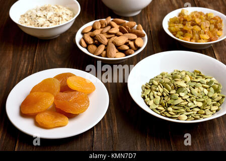 Snack sani nella ciotola. Ingredienti per la cottura di granola sul tavolo di legno. Foto Stock