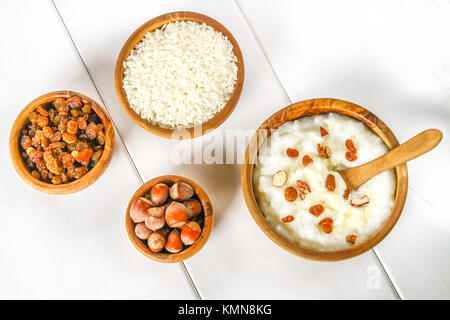 Latte di riso porridge con noci e uvetta in ciotole di legno su un bianco tavolo in legno Foto Stock