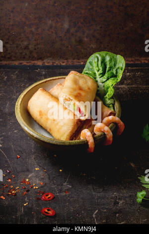 Fritti involtini primavera con verdure e gamberi, servito in tazza di ceramica su sfondo nero. Foto Stock