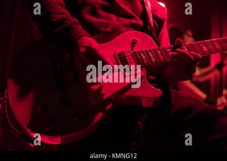 Il chitarrista suona la chitarra elettrica in un concerto, close-up, sotto illuminazione rossa Foto Stock