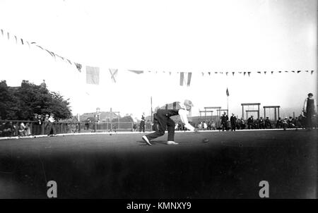 Match in azione nota le altalene per bambini in background. c1919 corona verde bocce, Inghilterra. Foto di Tony henshaw Foto Stock