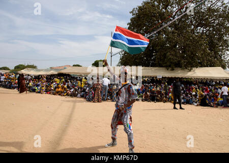 Giovane uomo è indossano i vestiti che rappresentano il presidente del Gambia Adama Barrow, sventolando nazionale bandiera del Gambia Foto Stock