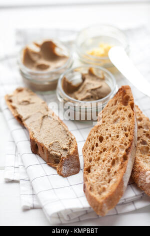 Pane con carne di vitello e patè di coniglio con burro su un sfondo di materie tessili. Foto Stock