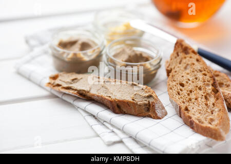 Pane con carne di vitello e patè di coniglio con burro su un sfondo di materie tessili. Foto Stock