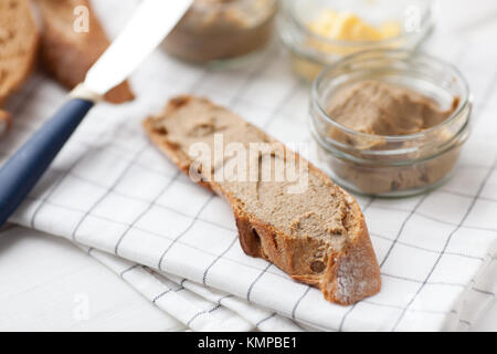 Pane con carne di vitello e patè di coniglio con burro su un sfondo di materie tessili. Foto Stock