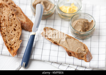 Pane con carne di vitello e patè di coniglio con burro su un sfondo di materie tessili. Foto Stock