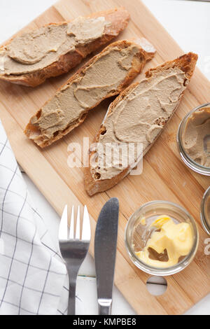 Pane con carne di vitello e patè di coniglio con burro su una scheda di bambù. Vista dall'alto. Foto Stock