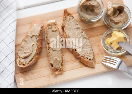 Pane con carne di vitello e patè di coniglio con burro su una scheda di bambù. Vista dall'alto. Foto Stock