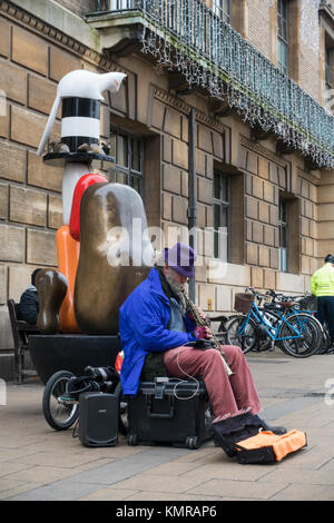 Busker suonare di fronte nevoso statua commemorativa Guildhall Market Square Cambridge Foto Stock