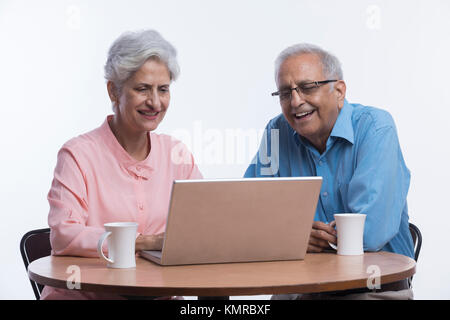 Coppia senior utilizzando laptop seduto sul tavolo Foto Stock