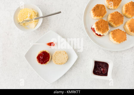 Focaccine con crema e confettura di fragole su marmo bianco dello sfondo. Vista dall'alto. Foto Stock