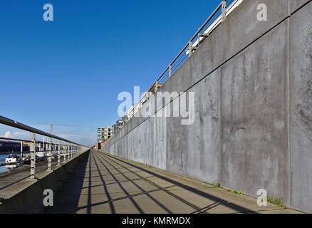 Esplanade lungo l'Europa porto di Brema, Germania con ringhiera in metallo grigio a parete in cemento, ormeggiata yacht a vela ed un cielo blu chiaro Foto Stock