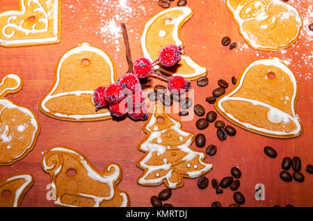 Gingerbreads Natale con glassa bianca, i chicchi di caffè e rowan ramoscello per decorazione su una tavola di legno Foto Stock