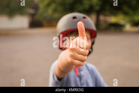 Ragazzo che mostra i pollici in su mentre si indossa il casco Foto Stock