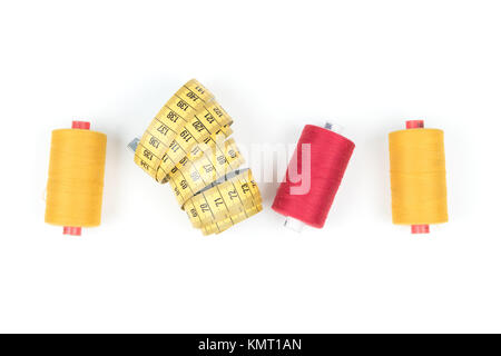 Filati per cucire di bobina giallo con nastro di misurazione su sfondo bianco Foto Stock