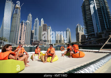 Le persone sulla barca catamarano di Dubai a guardare verso il cielo della città e cielo e raschiatori Foto Stock