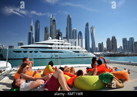 Le persone sulla barca catamarano di Dubai a guardare verso il cielo della città e cielo e raschiatori Foto Stock