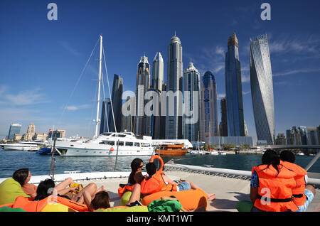 Le persone sulla barca catamarano di Dubai a guardare verso il cielo della città e cielo e raschiatori Foto Stock