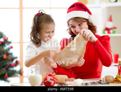 Madre e figlia la cottura biscotti di Natale a decorate albero. Mamma e Bambino cuocere i dolci di Natale. Famiglia con bambini festeggiano il Natale a casa. Foto Stock