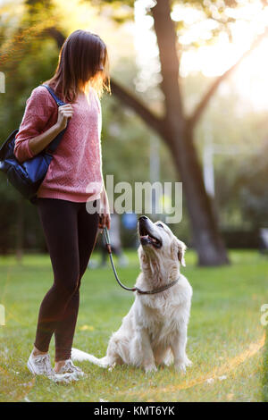 Immagine della giovane donna sulla passeggiata con retriever in estate park Foto Stock