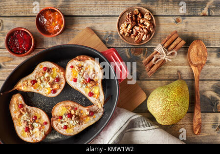 Le pere al forno con formaggio blu e wallnuts, servita con arancia e cowberry marmellata, cannella e zucchero in legno rustico sfondo. Vista superiore Foto Stock