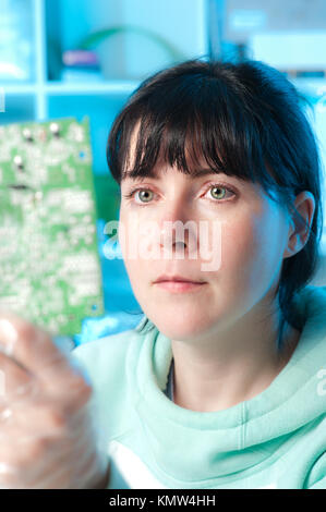 Riparazione di elettronica tech esamina una scheda curcuit Foto Stock