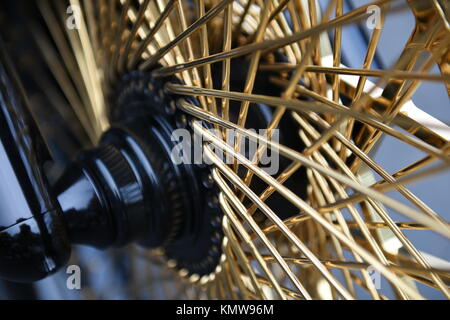 Moto ruota raggi oro, profondità di campo offuscata closeup di una ruota di moto chopper con un modello di raggi oro Foto Stock