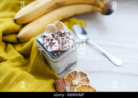 Budino cremoso con una banana, cioccolato e cannella su un sfondo marmo. Colazione Leggera. Vista dall'alto. Foto Stock