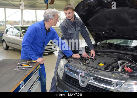 Studente di apprendimento meccanico da parte dell'insegnante in automotive scuola professionale Foto Stock