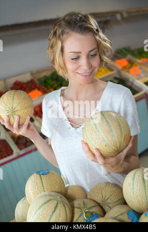 Donna scegliendo i meloni di supermercato Foto Stock