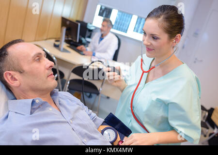 L'infermiera prendendo dell'uomo della pressione del sangue Foto Stock