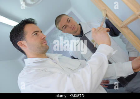 Apprendista guardando tradesman trattare la cornice in legno Foto Stock