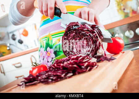 Donna con le mani in mano il taglio di cavolo rosso, dietro di verdure fresche. Foto Stock