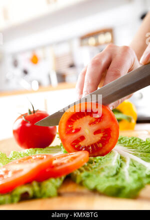 Donna con le mani in mano il taglio di pomodoro fresco su cucina Foto Stock