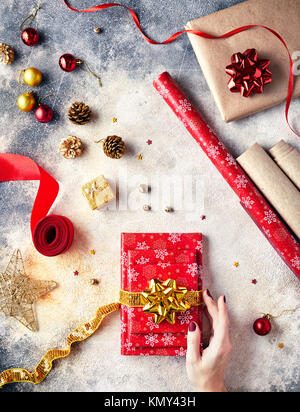 Donna che mantiene rosso avvolto presente con golden bow sul Natale Foto Stock
