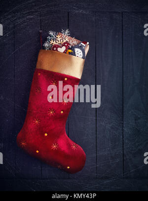 Calza rossa con regali e giocattoli su sfondo di legno sul Natale Foto Stock