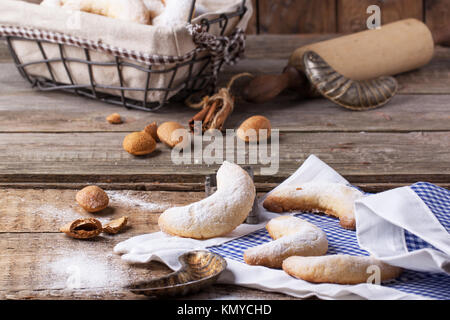 Lo zucchero in casa cookie crescent servita con accessori vintage, mandorle e spezie su un vecchio tavolo in legno Foto Stock