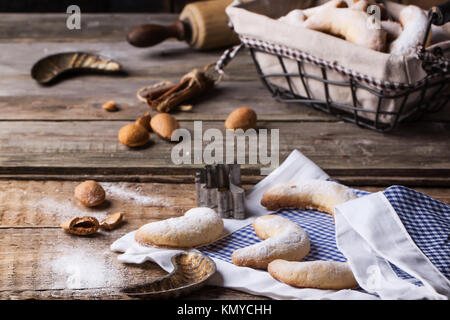 Lo zucchero in casa cookie crescent servita con accessori vintage, mandorle e spezie su un vecchio tavolo in legno Foto Stock