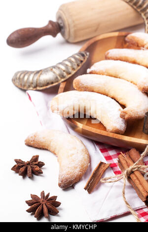 In casa i cookie di zucchero a mezzaluna in legno con il matterello e spezie su bianco Foto Stock