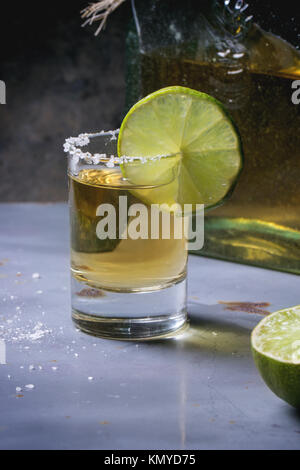 A corto di tequila anejo con calce e sale di metallo grigio nella tabella Foto Stock